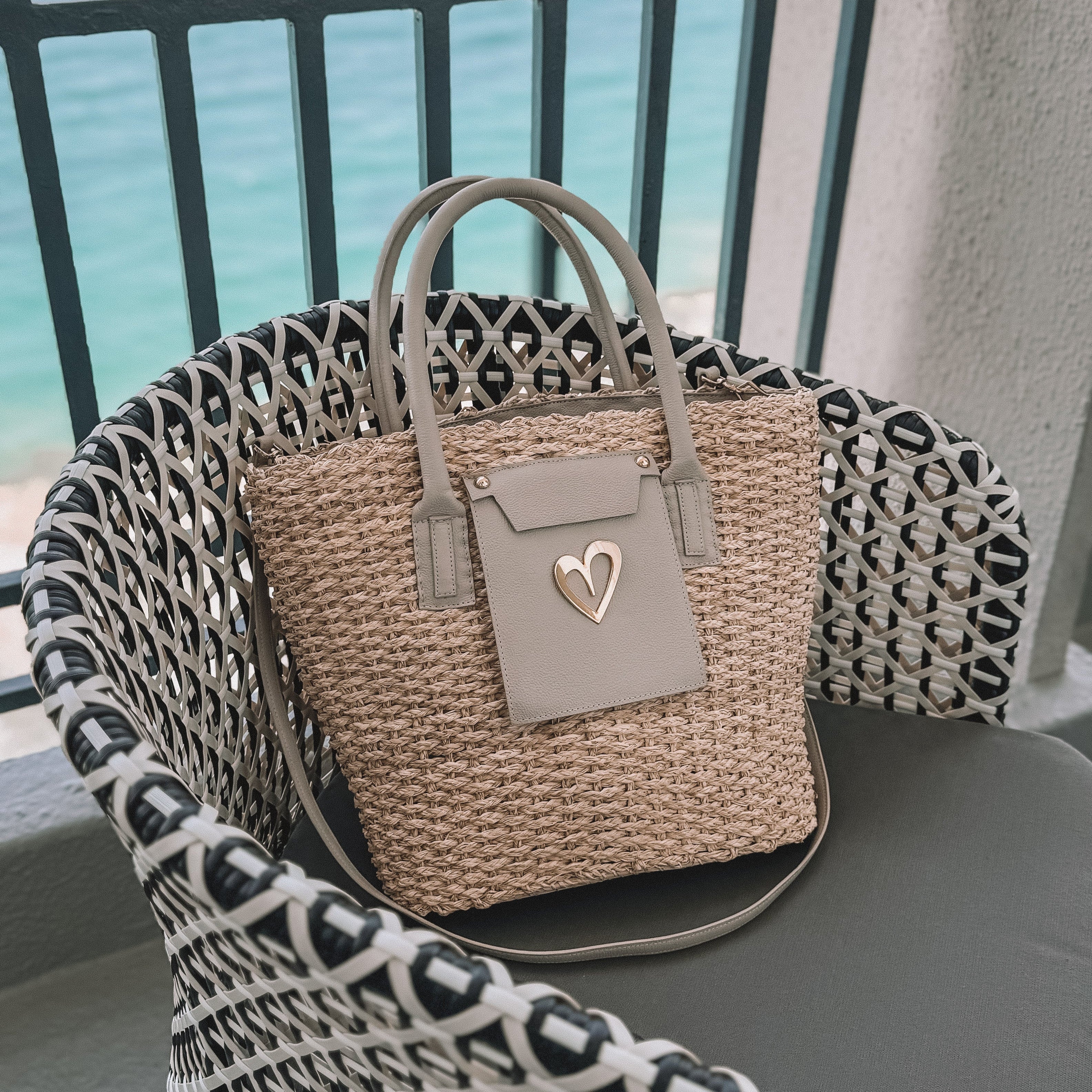 Love Beach Straw Basket by Nataly Mendez, Shell material: Natural straw and genuine leather Lining: Waterproof Genuine Leather handles Two top handles and a strap (dual use) Slip pocket and a zip pocket at the interior 12" H X 16" L x 3.5" D, 8.5" handle drop Wipe clean Handmade